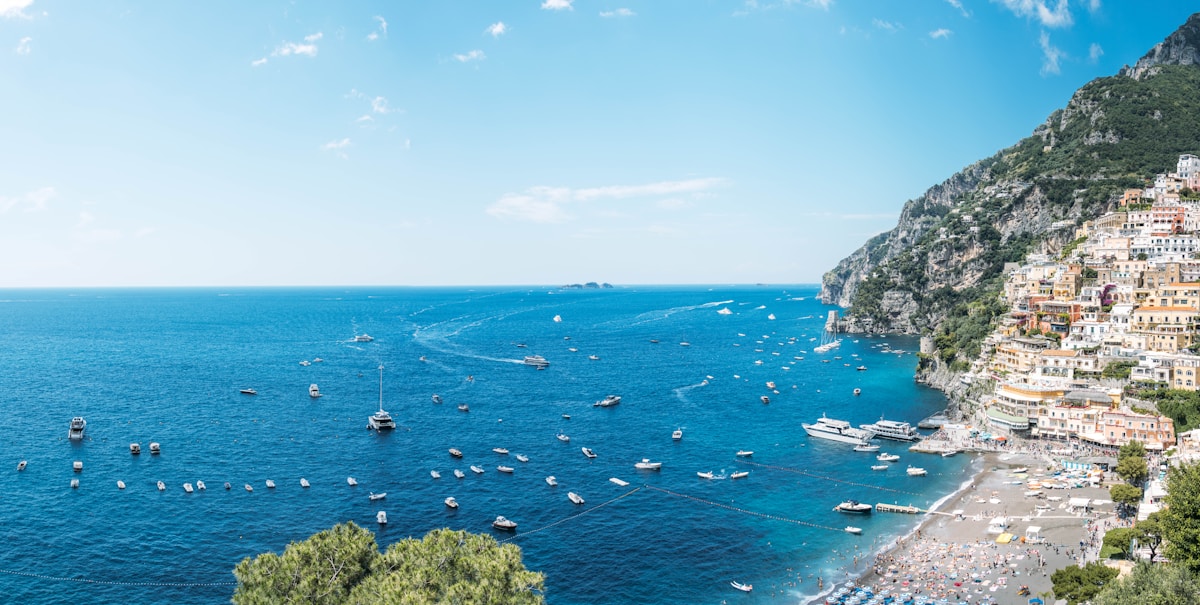 Aerial view of Positano town with dozens of boats anchored in the clear blue water of the Amalfi Coast