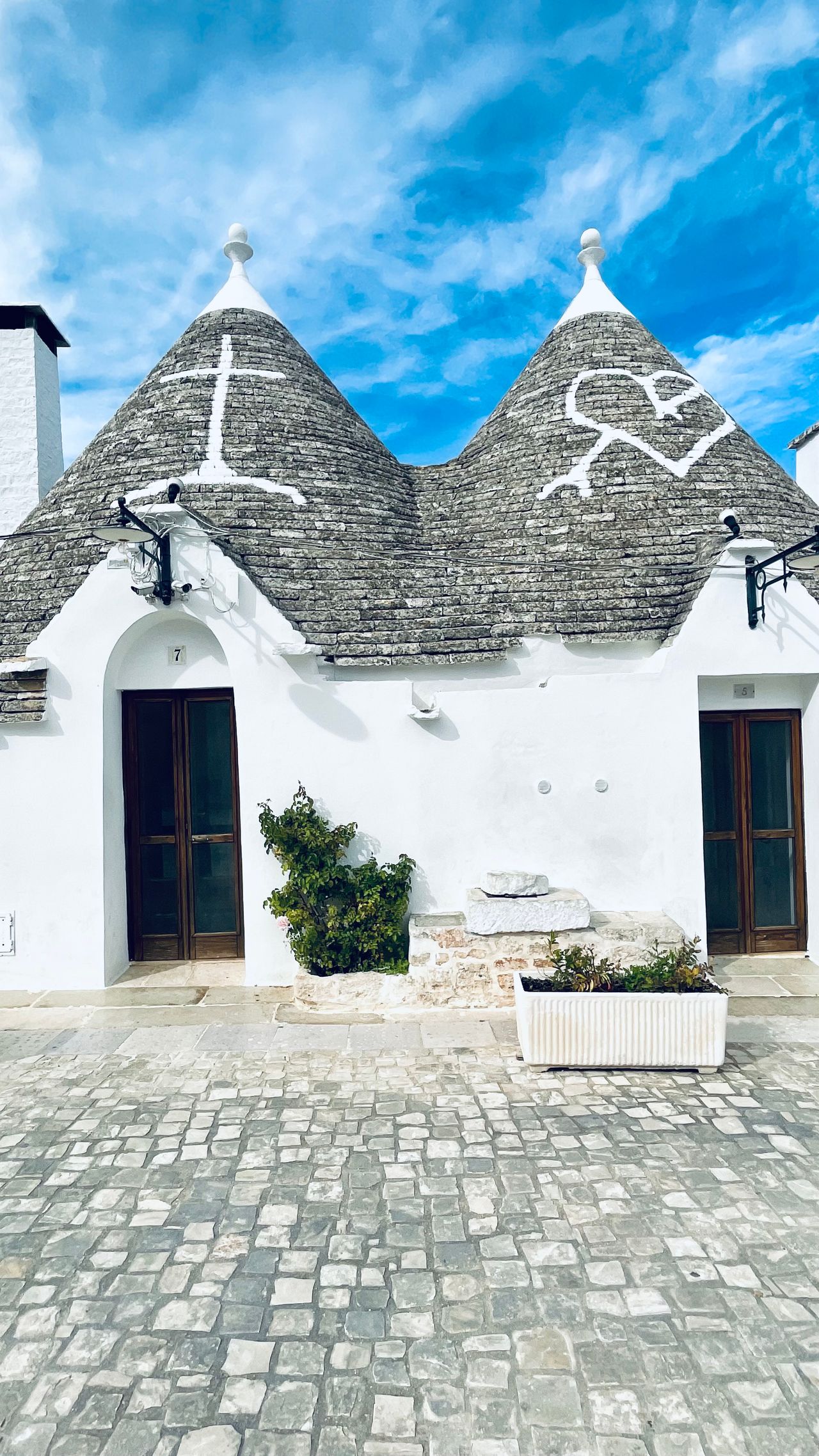 White trulli limestone houses with conical stone roofs on a cobblestone street in Alberobello, Puglia, Italy