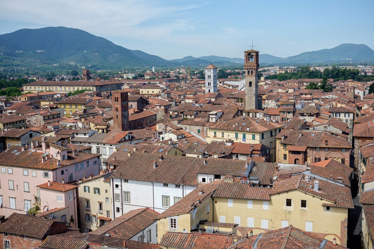 Terracotta rooftops and medieval stone towers of historic Lucca seen from the city walls, Tuscany, Italy