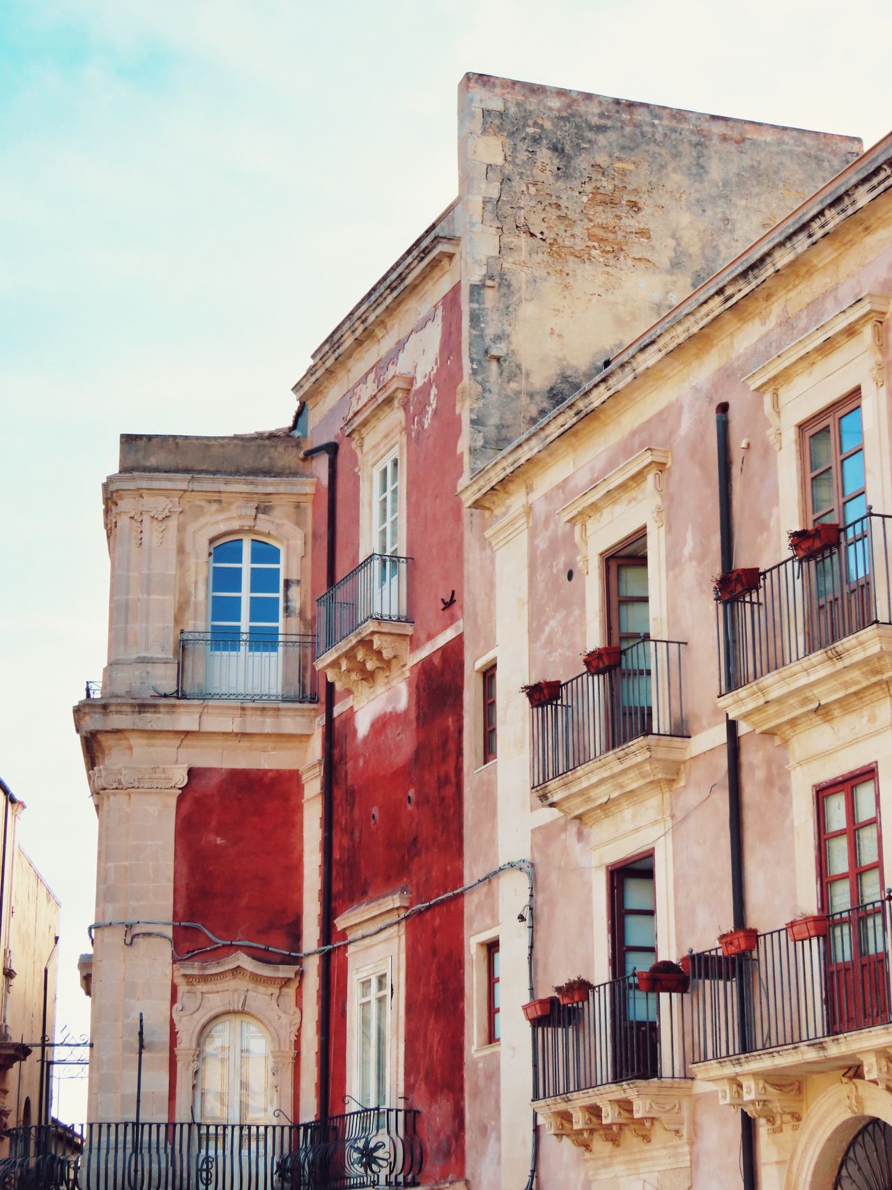 Ornate Baroque buildings with iron balconies on a narrow street of Ortigia island, Syracuse, Sicily, Italy