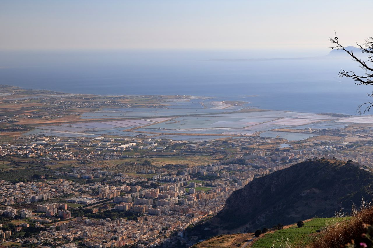 Aerial view of Trapani coastline with salt pans reflecting the sky and the blue Mediterranean sea, Sicily, Italy