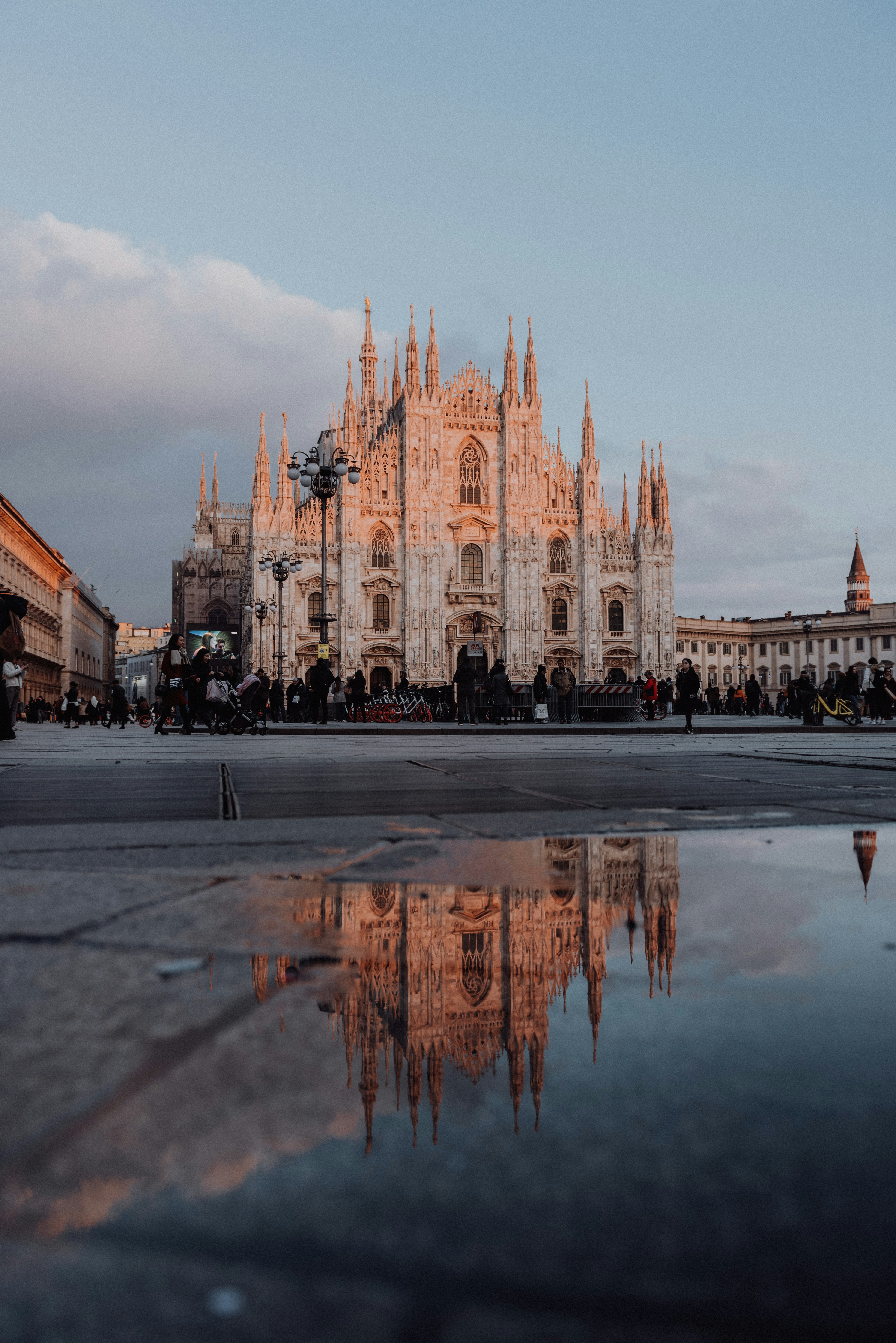 Milan Duomo cathedral with Gothic spires reflected in a puddle at sunset, Piazza del Duomo, Milan, Italy