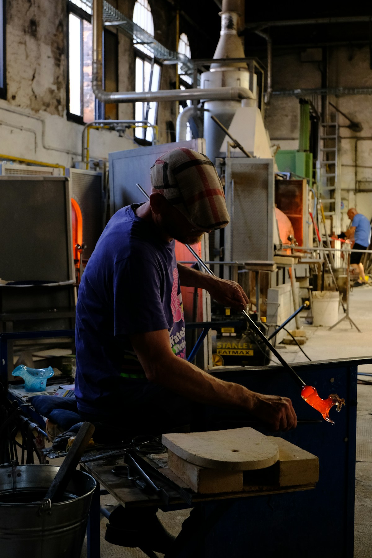 Glassblower working with molten glass in a Murano furnace workshop, Venice, Italy