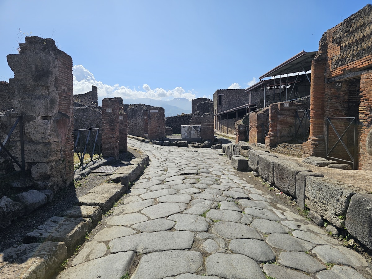 Stone-paved street between ruined houses in ancient Pompeii, Italy