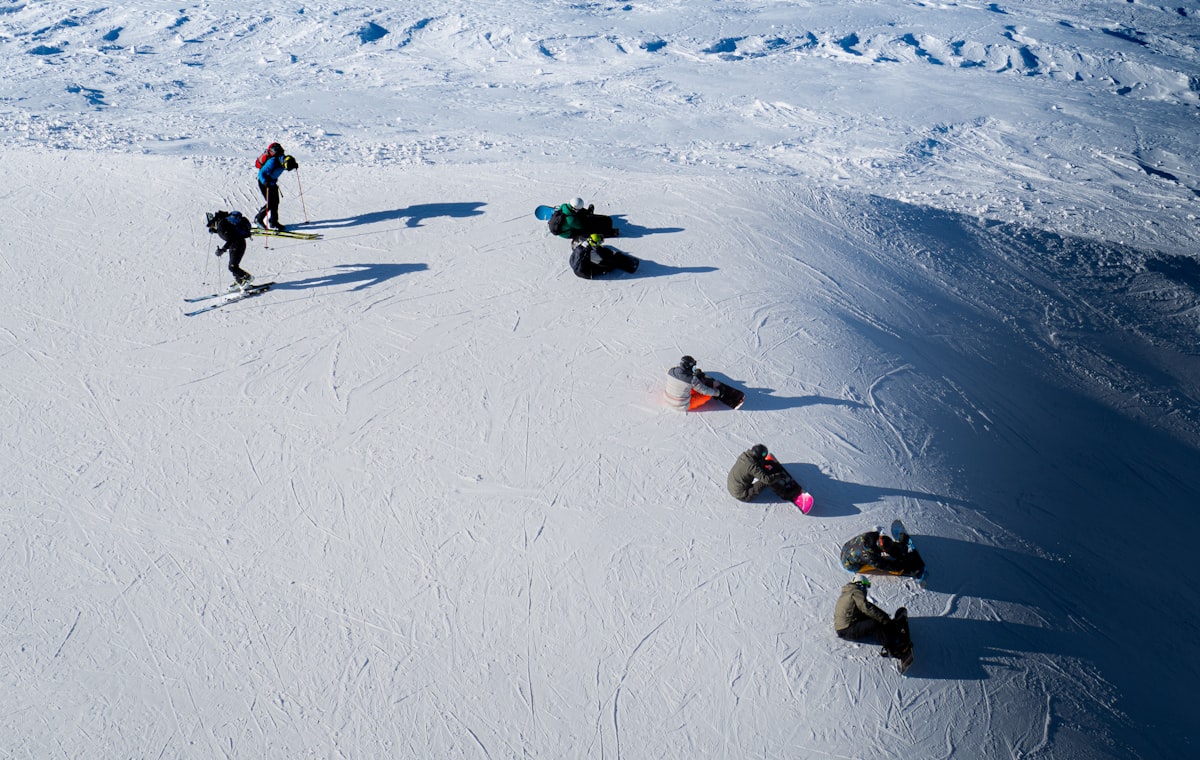 Skiers and snowboarders descending a wide groomed piste in the Dolomites, Italy, seen from above