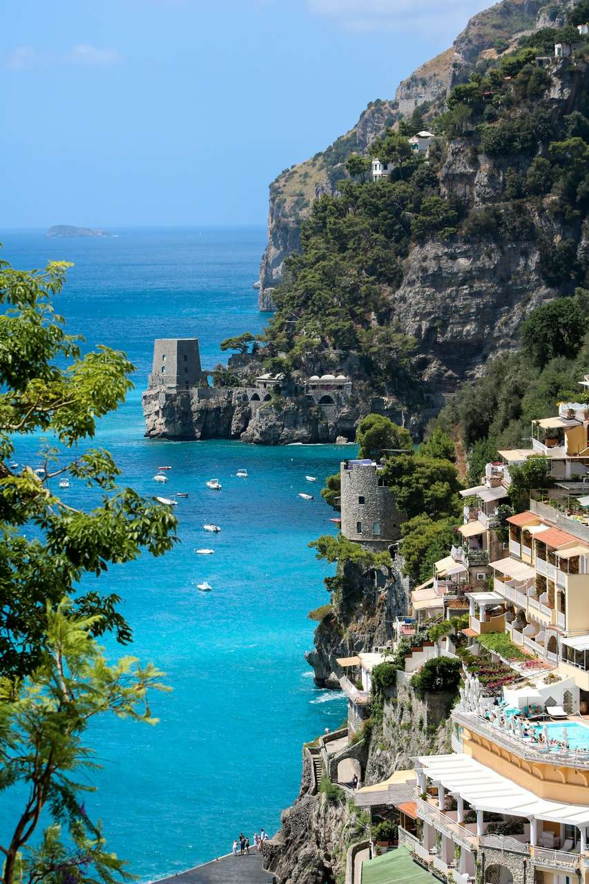 Amalfi town from the sea with medieval towers, cliffside buildings and turquoise Mediterranean water