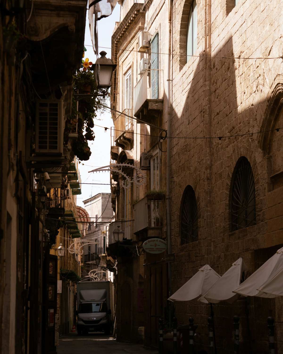 Narrow stone alleyway with strong light and shadow between old buildings in Bari Vecchia, Puglia, Italy