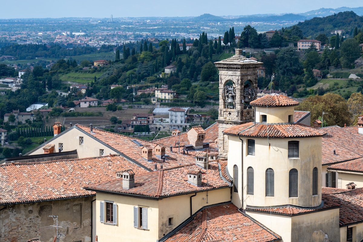 Terracotta rooftops and bell tower of Bergamo Alta with the Lombard plain stretching below, Italy