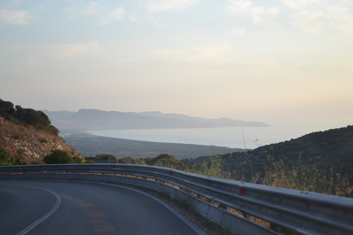 Curving coastal road overlooking the sea at sunset, Sardinia, Italy