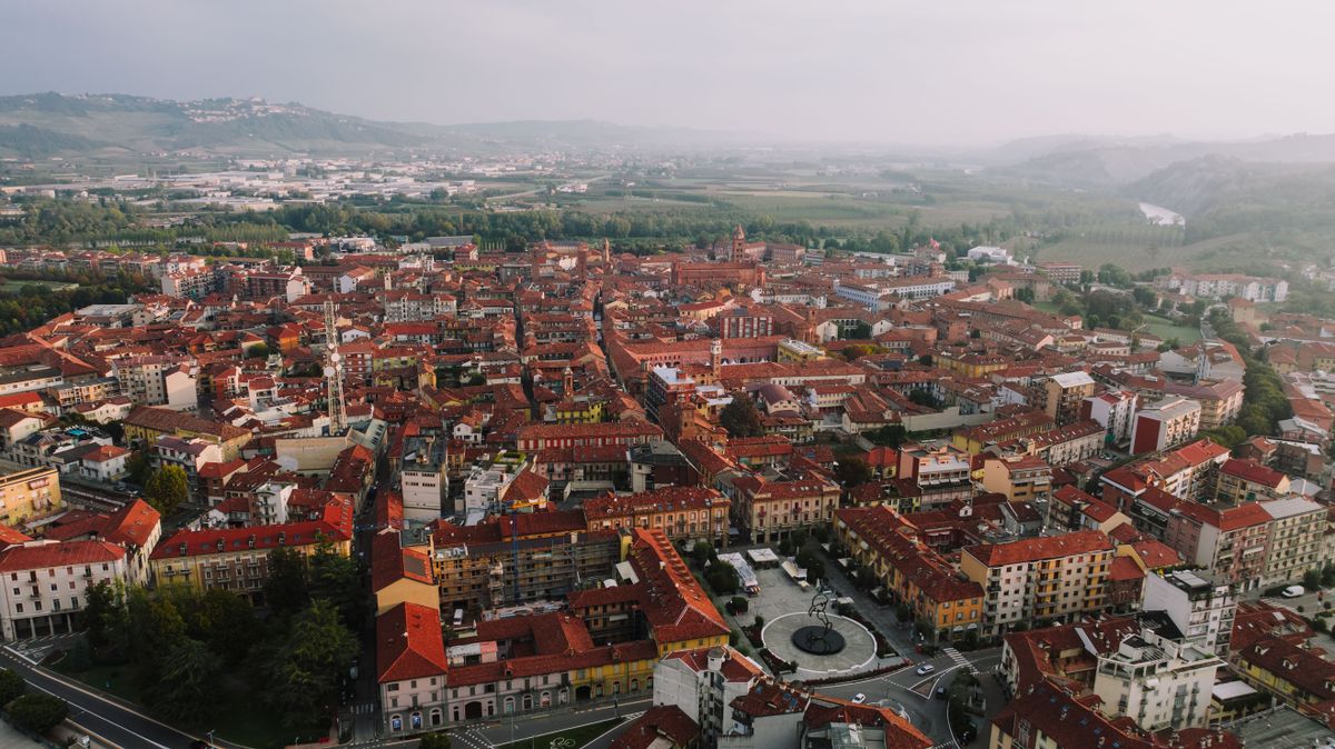 Aerial view of Alba historic centre with terracotta rooftops and Piedmont wine country hills, Italy
