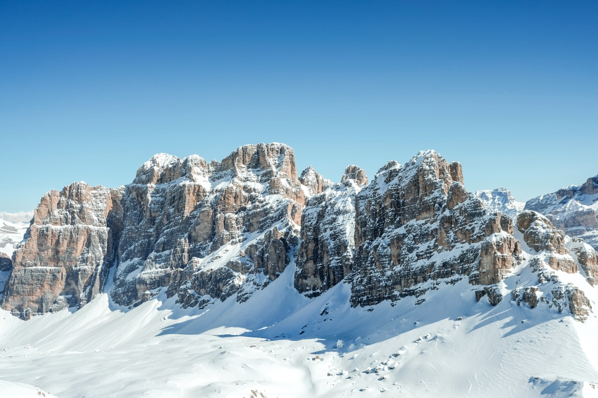 Snow-covered Dolomite rock towers rising against a clear blue winter sky, South Tyrol, Italy