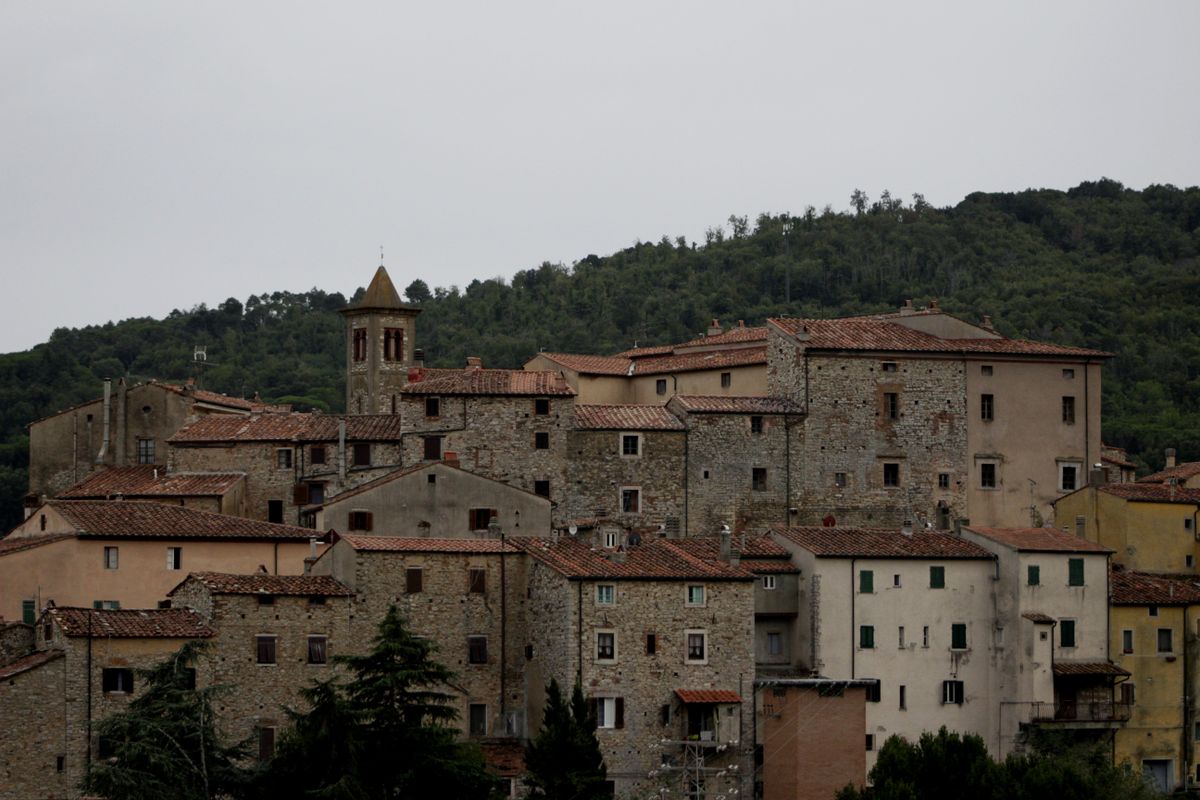 Panoramic view from Cortona's medieval walls across the Val di Chiana with Lake Trasimeno visible in the distance