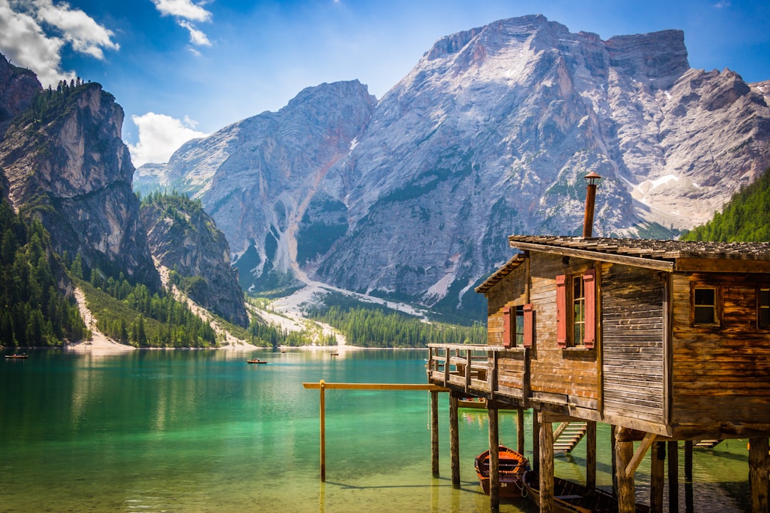 Rustic wooden boathouse on the turquoise waters of Lago di Braies with Dolomite peaks behind, South Tyrol