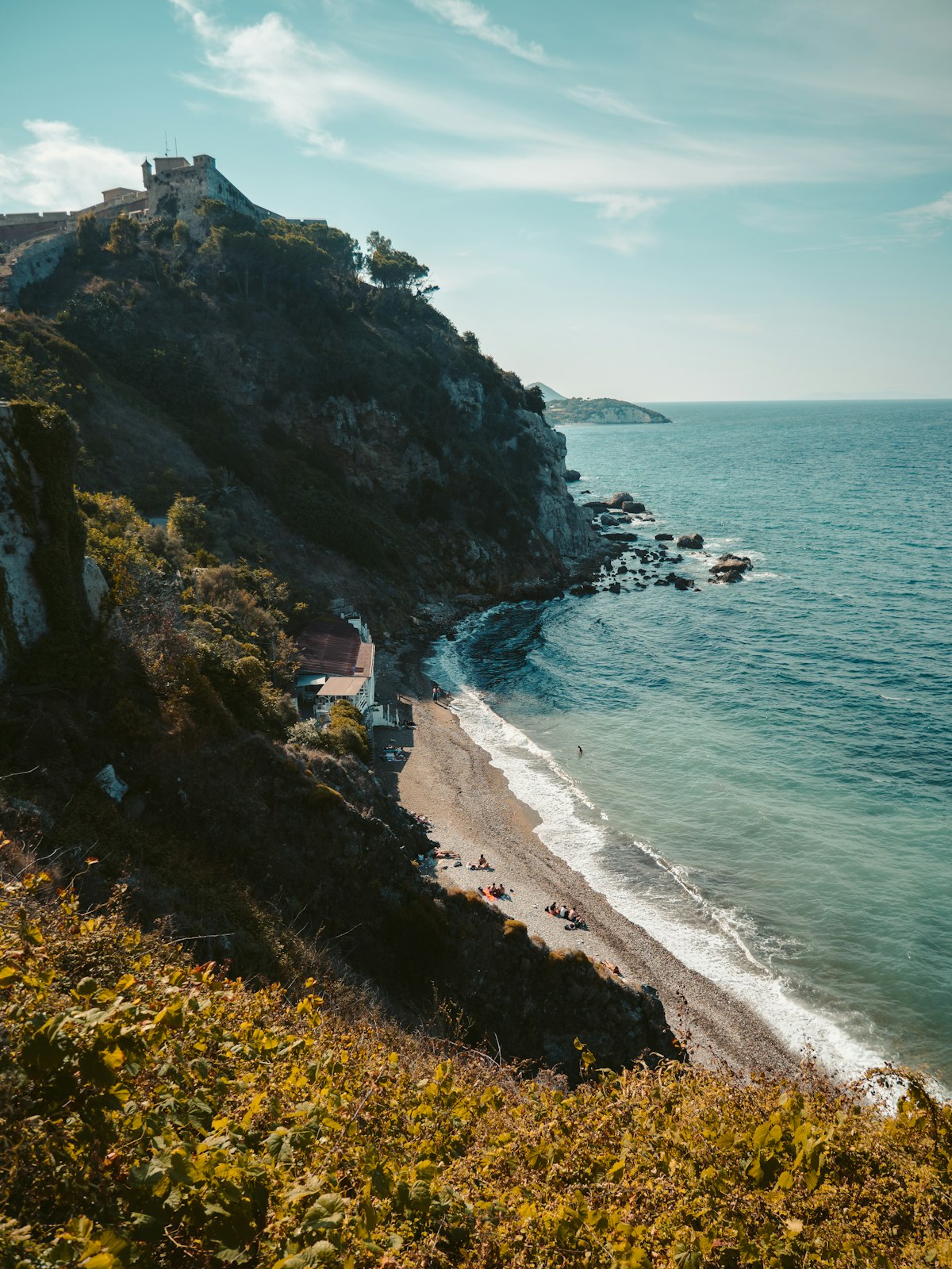 Rocky beach below a fortress cliff with crystal-clear sea, Elba island, Tuscany, Italy