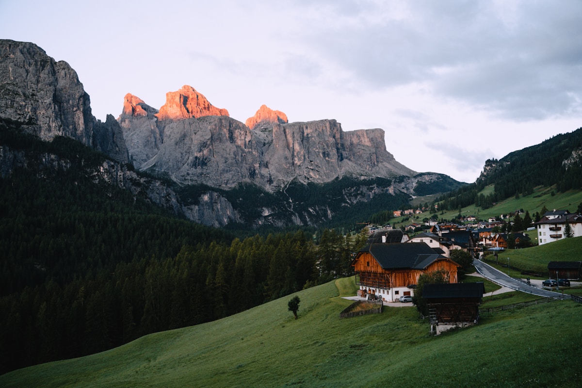 A mountain village with timber chalets below Dolomite peaks at alpenglow, Val Gardena, northern Italy