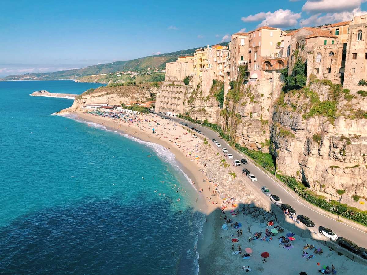 Aerial view of Tropea's clifftop town and beach below, with the sea and Santa Maria dell'Isola in the distance, Calabria, Italy