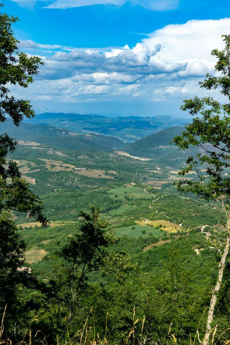 Green Umbrian valley landscape viewed from above with forested hills, Umbria, Italy