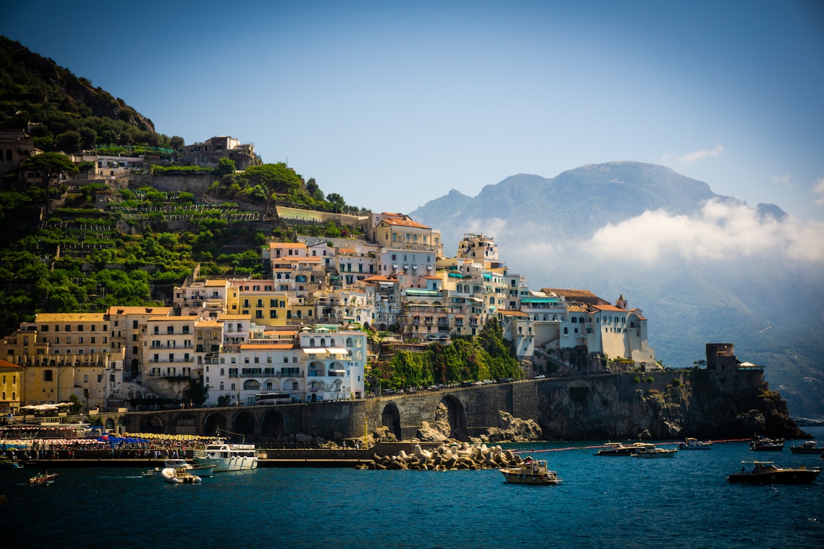 The town of Amalfi on its clifftop with terraced buildings and boats in the harbour, Amalfi Coast, Campania, Italy
