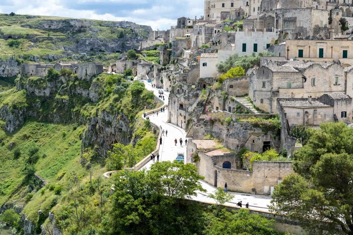 Visitors walking a winding road through the ancient Sassi cave city of Matera, Basilicata, Italy