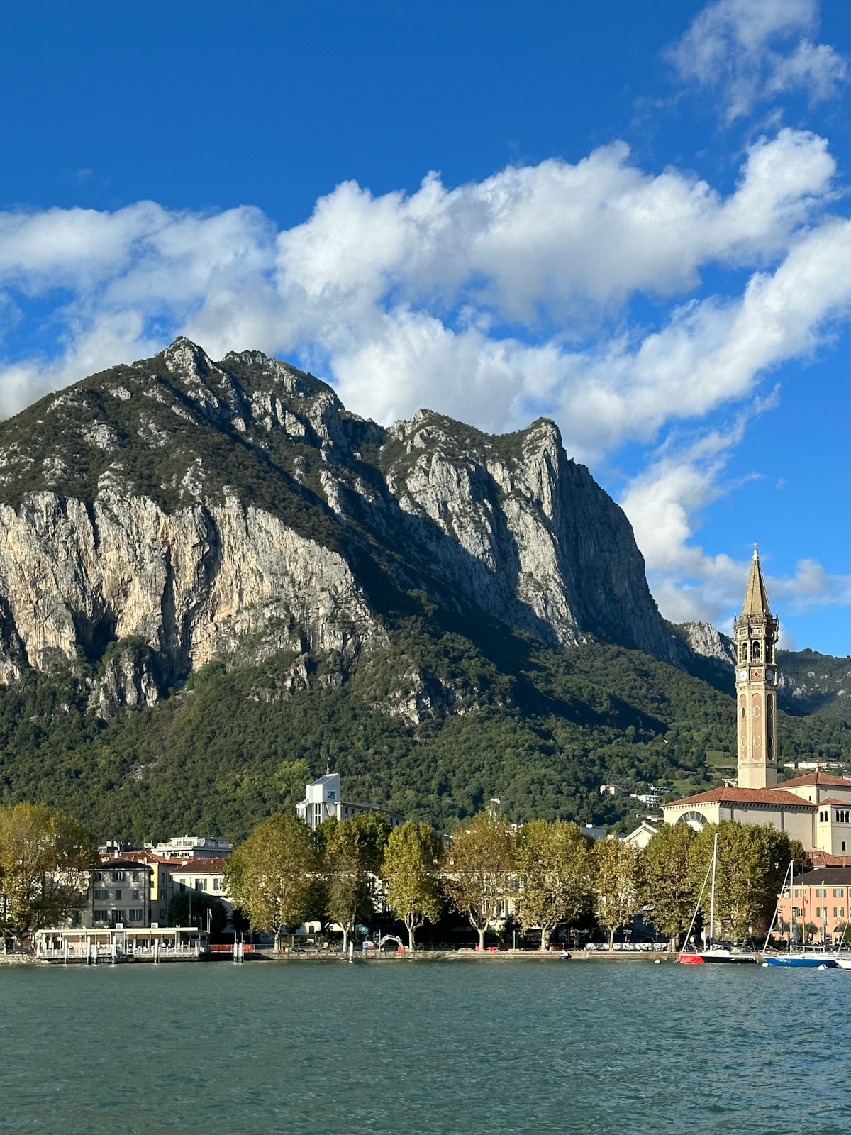 Lakeside town with church steeple and dramatic mountains, Lake Como area — classic day trip from Milan