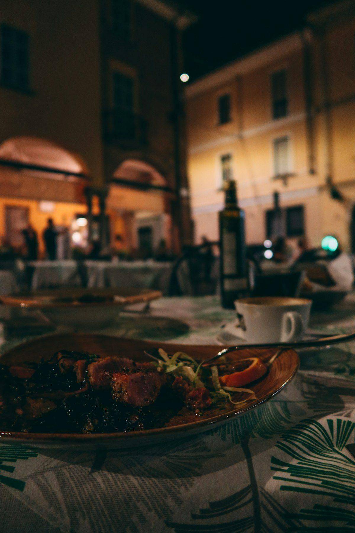 Outdoor restaurant table with a northern Italian meal and wine, evening street scene
