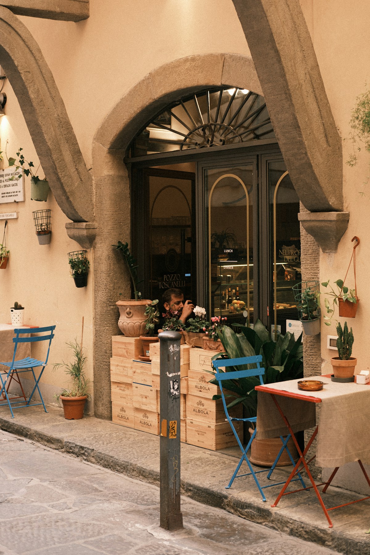 Outdoor cafe seating with potted plants and arched entrance, Italy