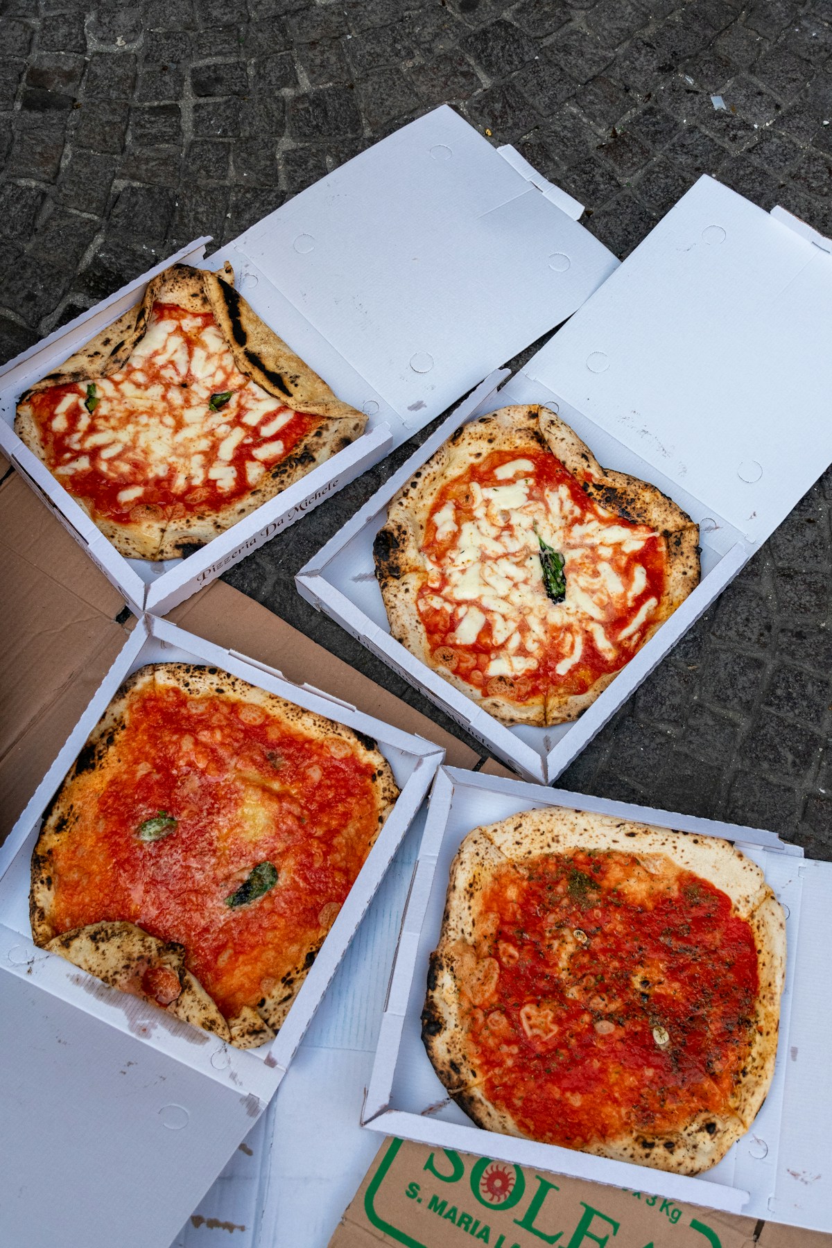 Neapolitan pizzas in boxes on a cobblestone street, Naples, Italy