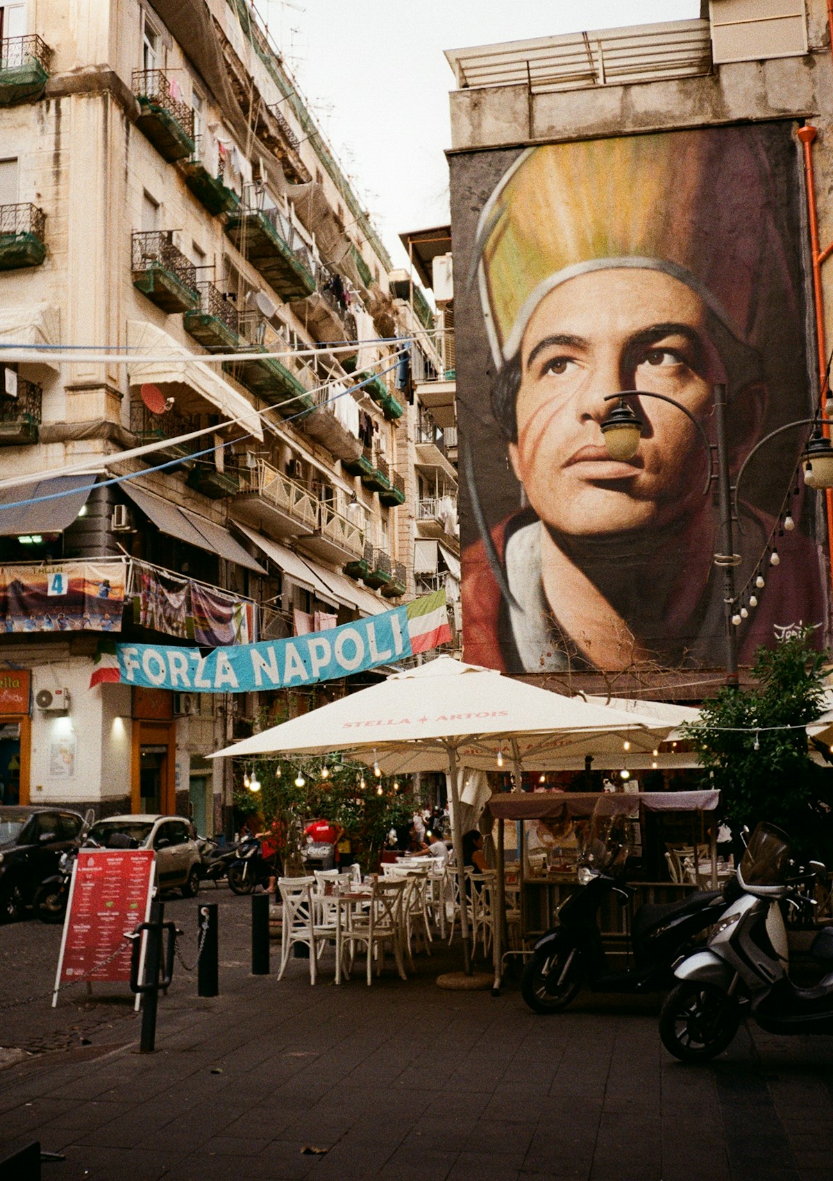 Mural of a man above an outdoor cafe, Naples, Italy