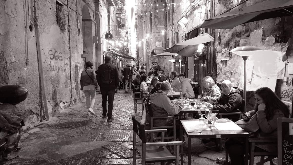 Diners eating at outdoor tables in a narrow Naples alleyway, Campania, Italy