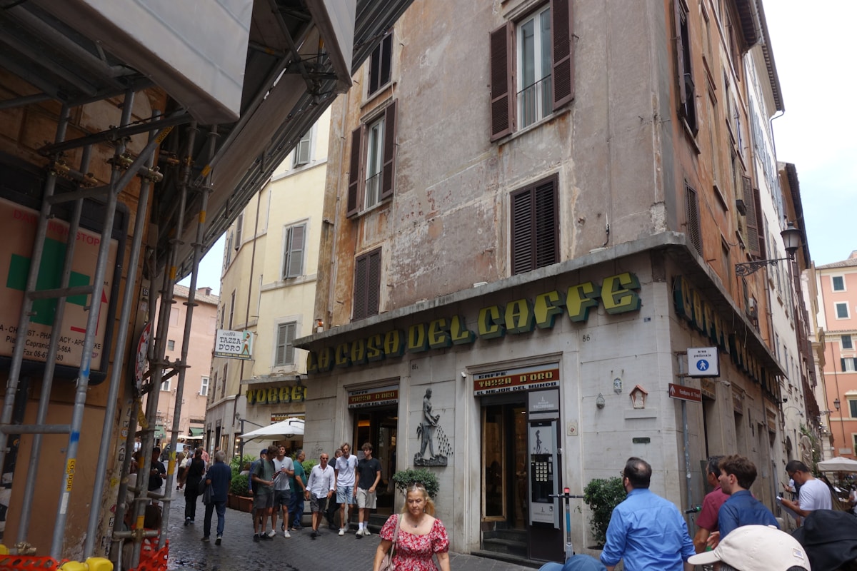 People walk past a cafe on a narrow street, Italy