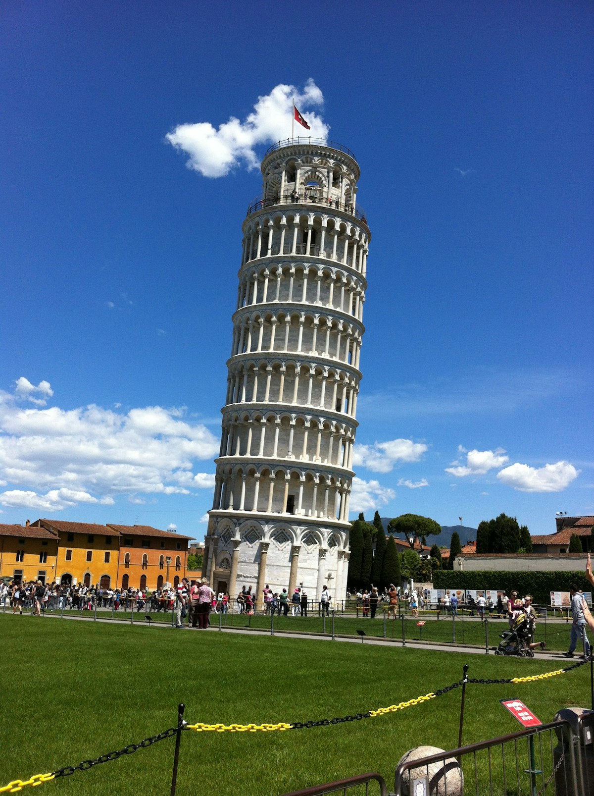 People walking on the green lawn of Piazza dei Miracoli near the Leaning Tower of Pisa, Tuscany, Italy