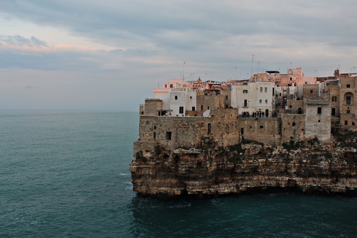White buildings of Polignano a Mare perched on limestone cliffs above the Adriatic sea, Puglia, Italy
