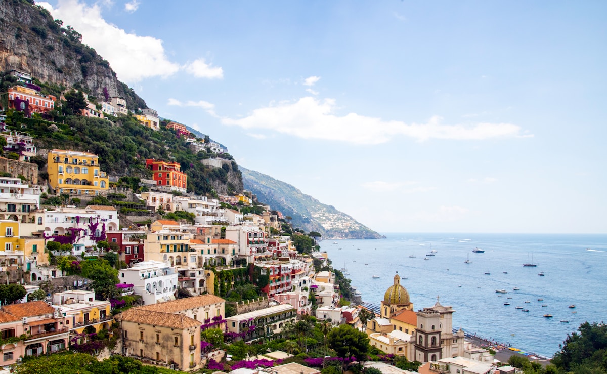 Positano's colourful cascade of buildings clinging to the cliffs above the Tyrrhenian Sea, with boats in the bay below