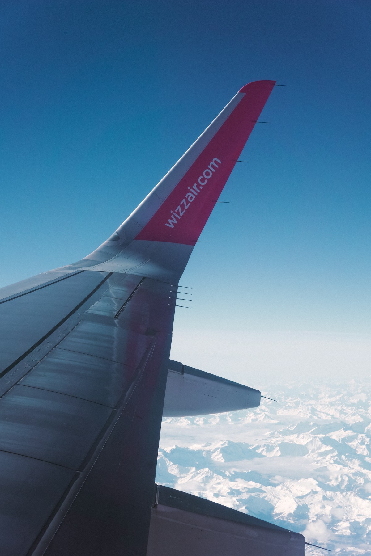 Airplane wing over the snow-covered Alps en route to Italy