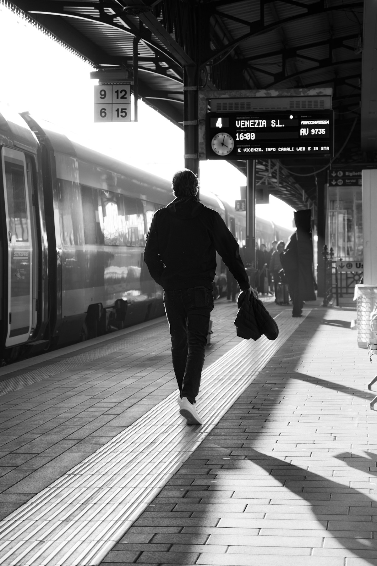 Passenger walking along a platform at an Italian station beside a Frecciarossa train bound for Venice