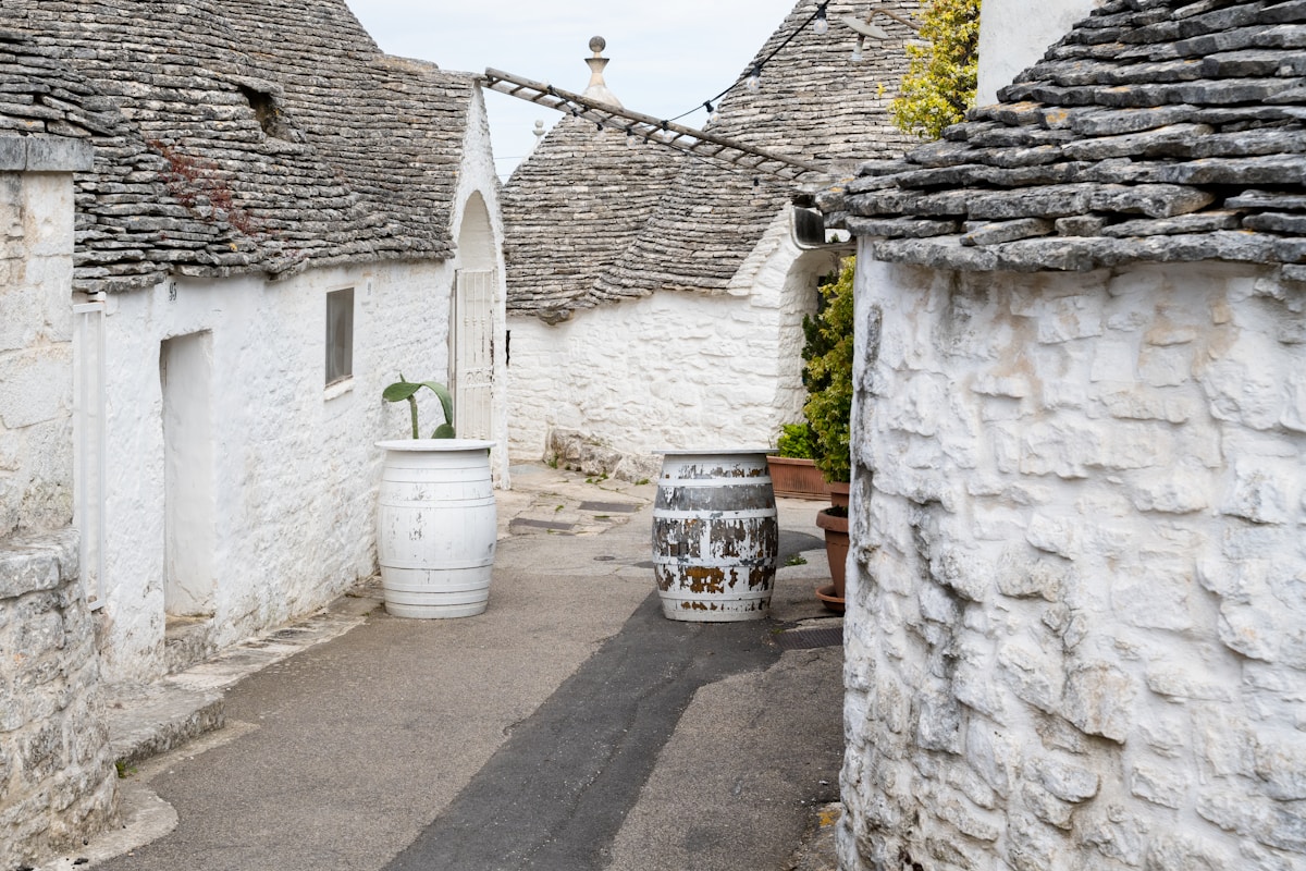 Narrow alley between white trulli houses with stone roofs, Alberobello, Puglia, Italy
