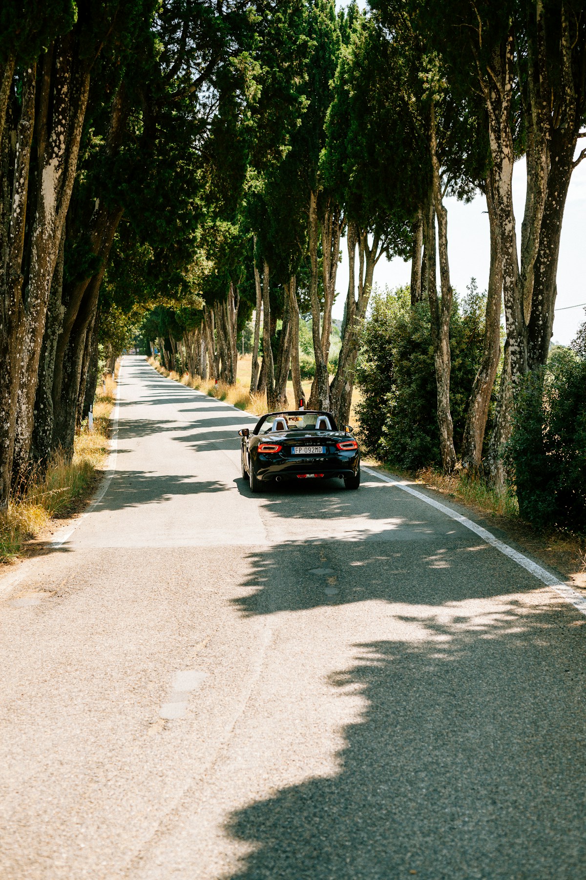 A car parked on a winding road in the Italian countryside