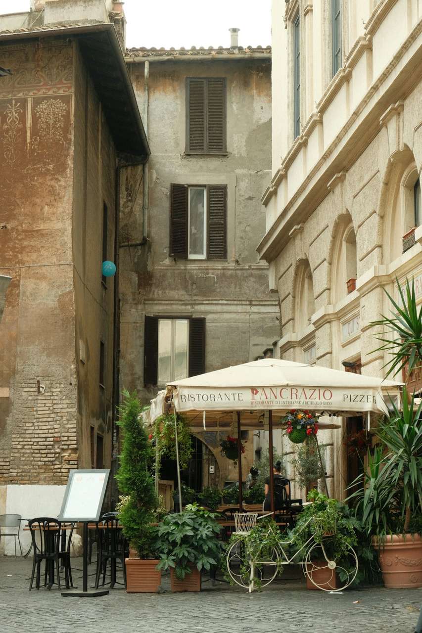 Outdoor trattoria tables between stone buildings in an Italian old town at dusk