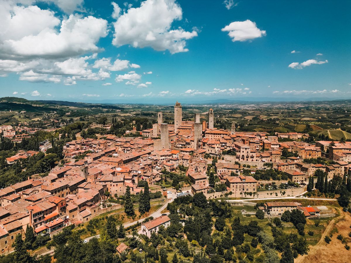 Medieval towers of San Gimignano rising above terracotta rooftops against a blue Tuscan sky
