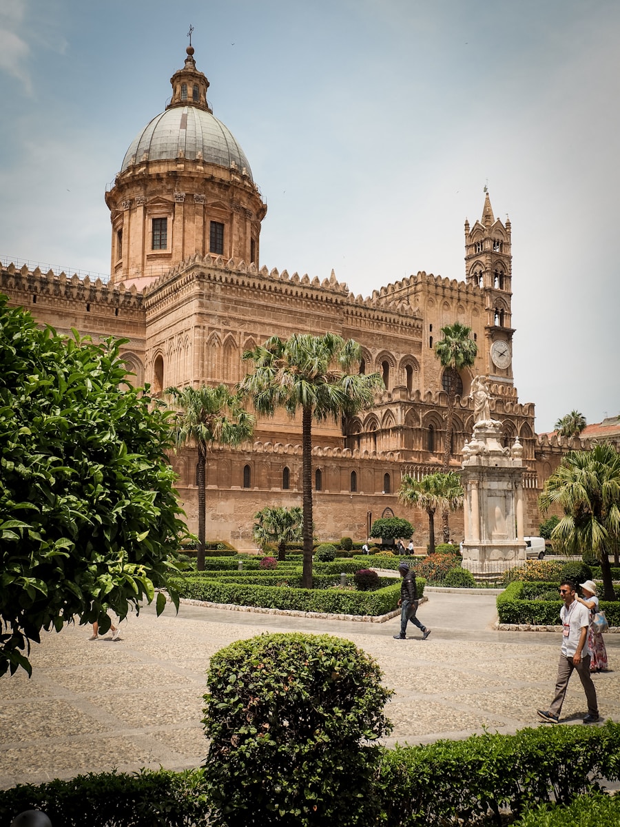 Cathedral of Palermo with ornate baroque facade, palm trees, and garden, Sicily, Italy