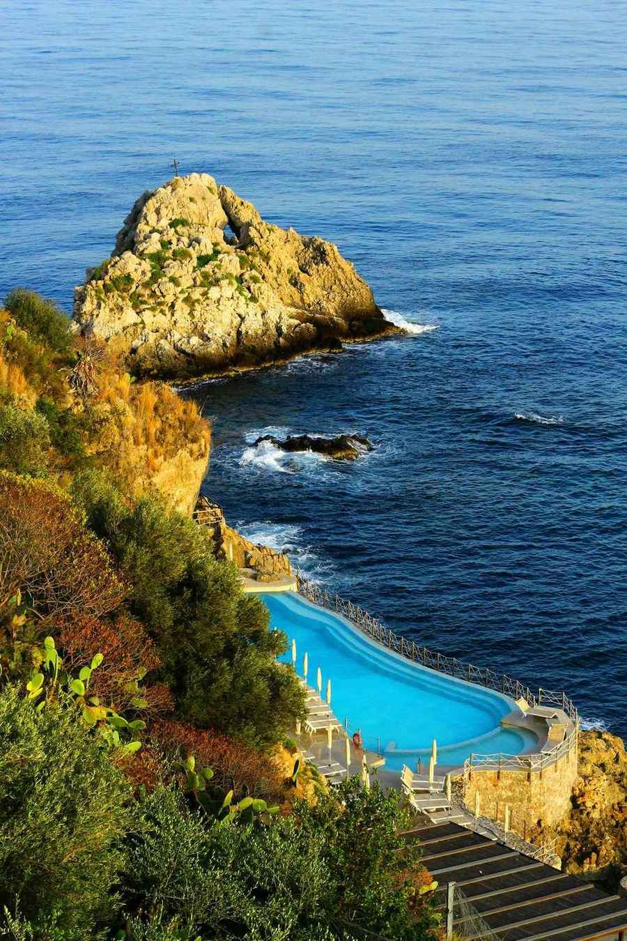 Infinity pool on a cliff above the Mediterranean Sea with rocky islets visible below, Taormina, Sicily, Italy