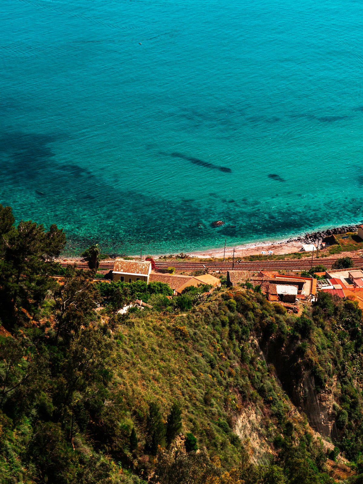 Aerial view of Taormina coastline with turquoise sea and terracotta rooftops, Sicily, Italy