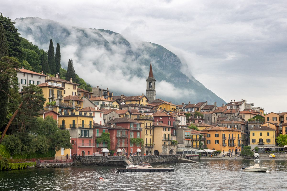 Varenna village on the shore of Lake Como with colourful buildings and Alpine mountains behind, Lombardy, Italy