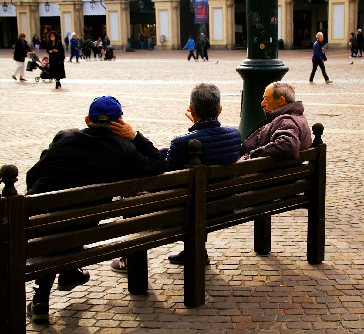 People sitting on a bench in a cobblestone piazza in Turin, Piedmont, Italy
