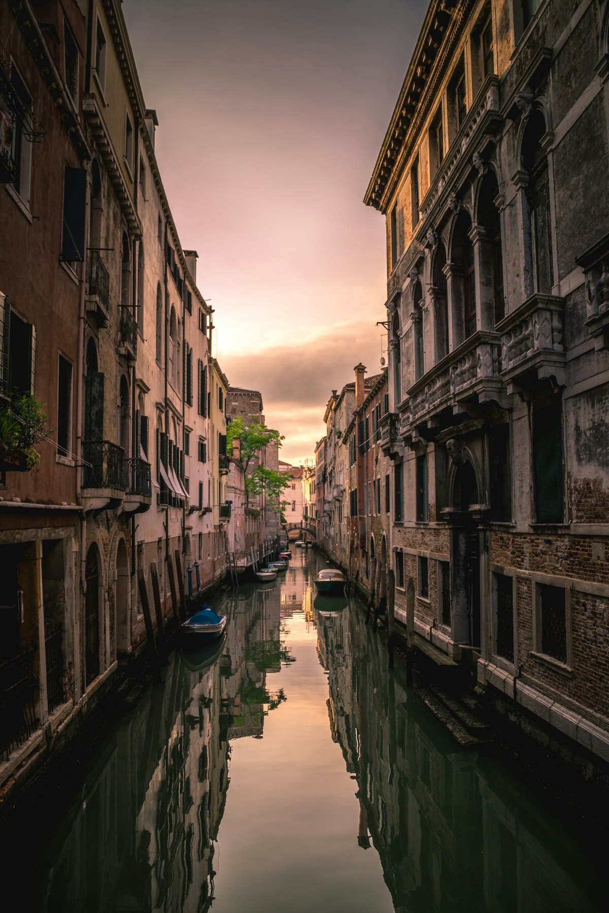 Narrow Venice canal at sunset with historic buildings reflected in the still water, Italy