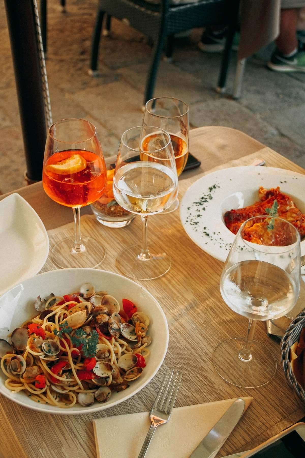 Spaghetti alle vongole with Aperol spritz at an outdoor lakeside restaurant table, northern Italy