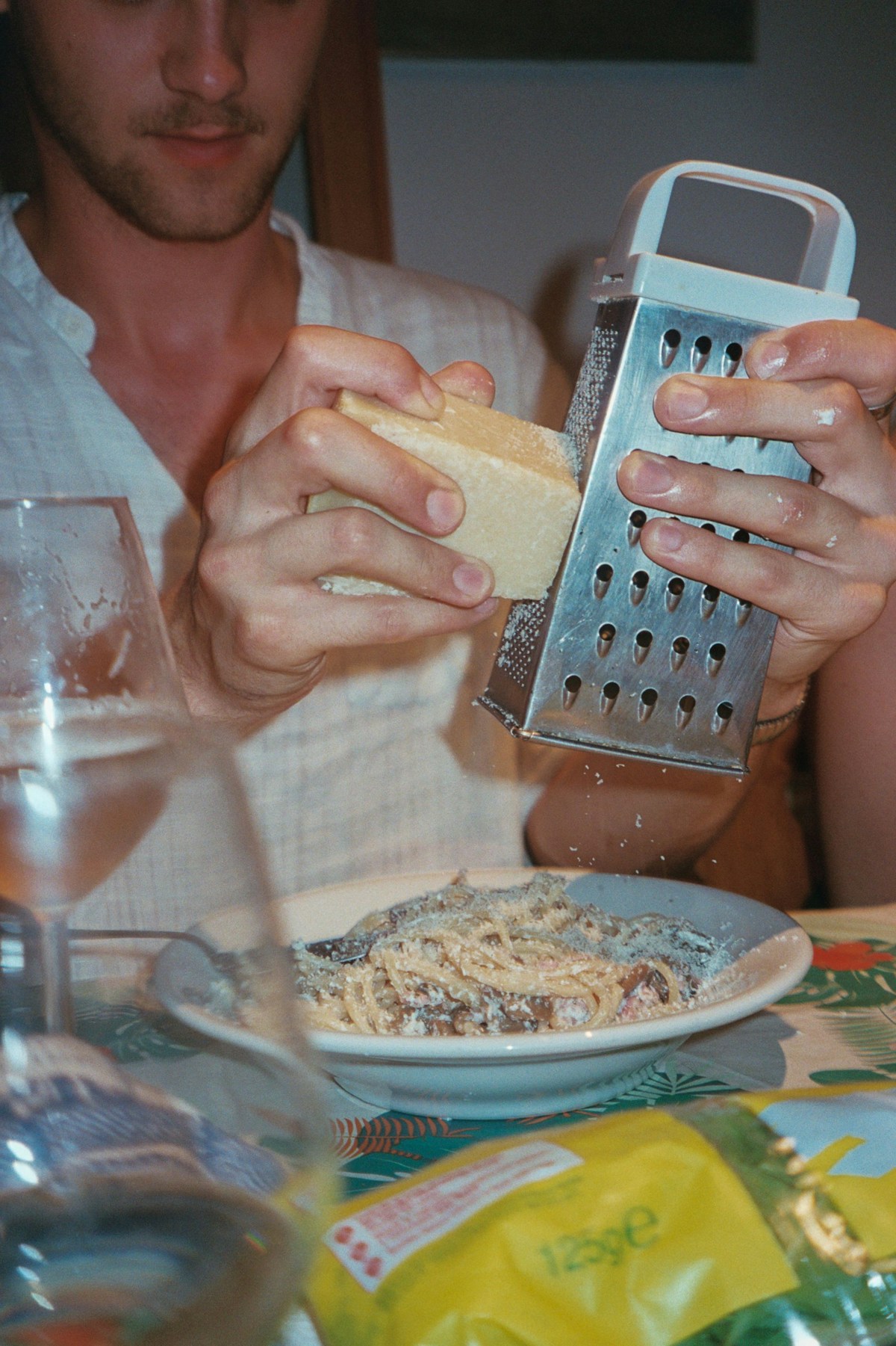 Person grating parmesan over a bowl of pasta, Venice, Veneto, Italy
