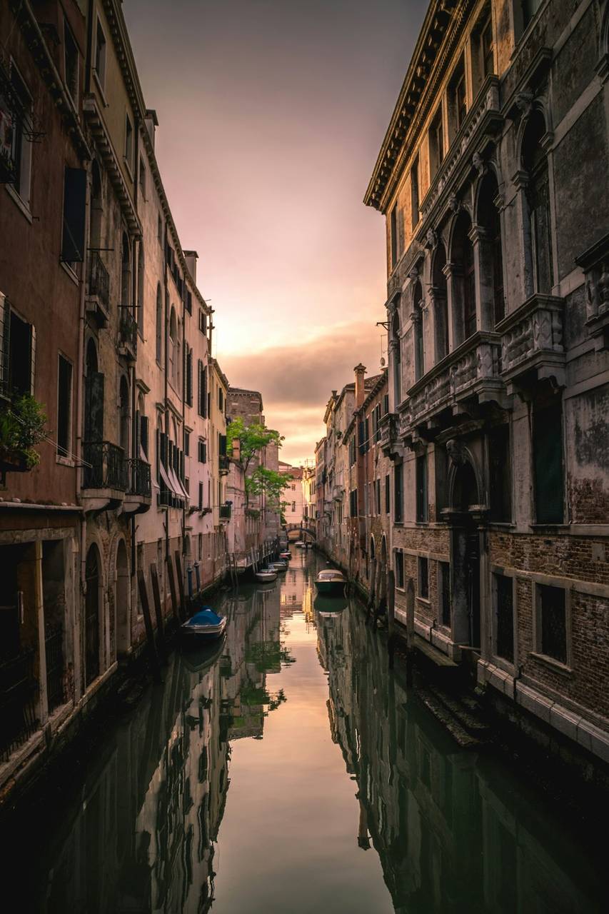 Venice canal at dusk with historic buildings reflected in still water