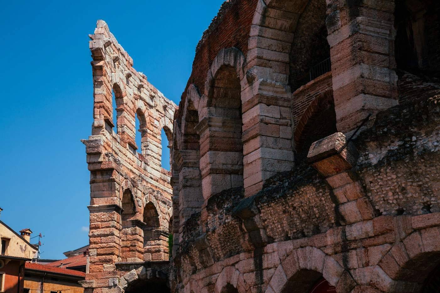 Ancient stone arches of the Arena di Verona Roman amphitheatre against a deep blue sky, Veneto, Italy