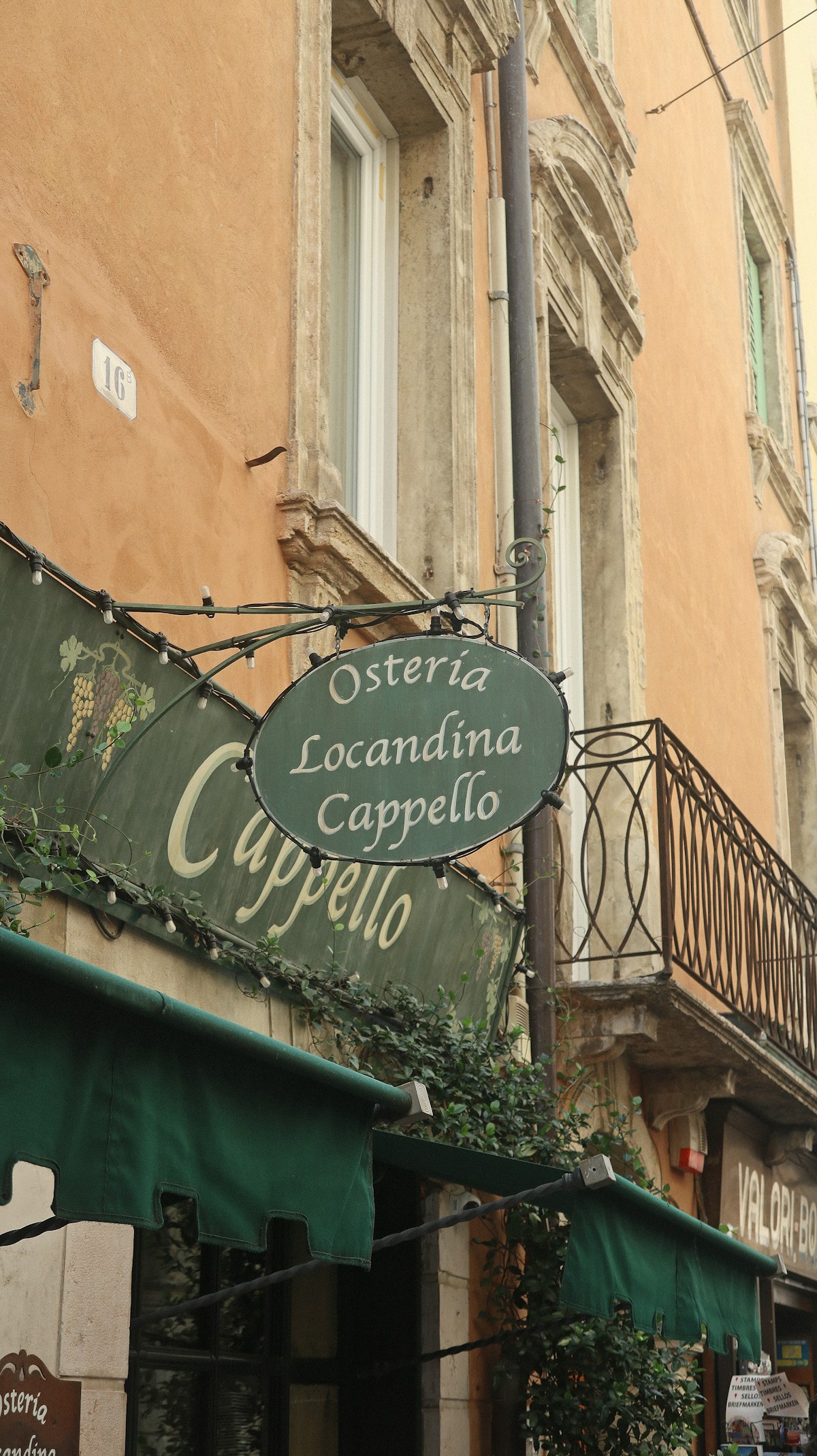 Osteria Locandina Cappello sign above a green awning on a Verona street, Veneto, Italy